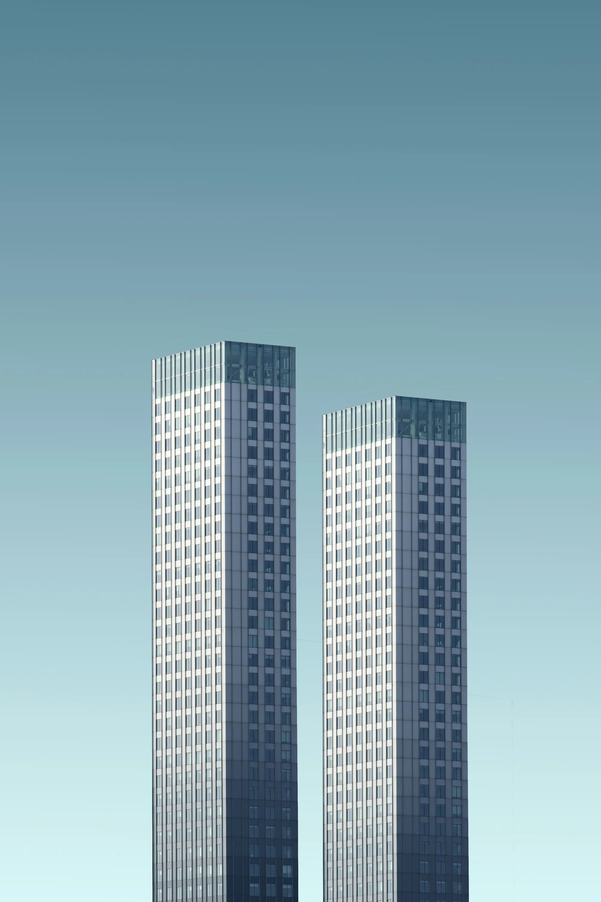 Two white office towers against a clear sky